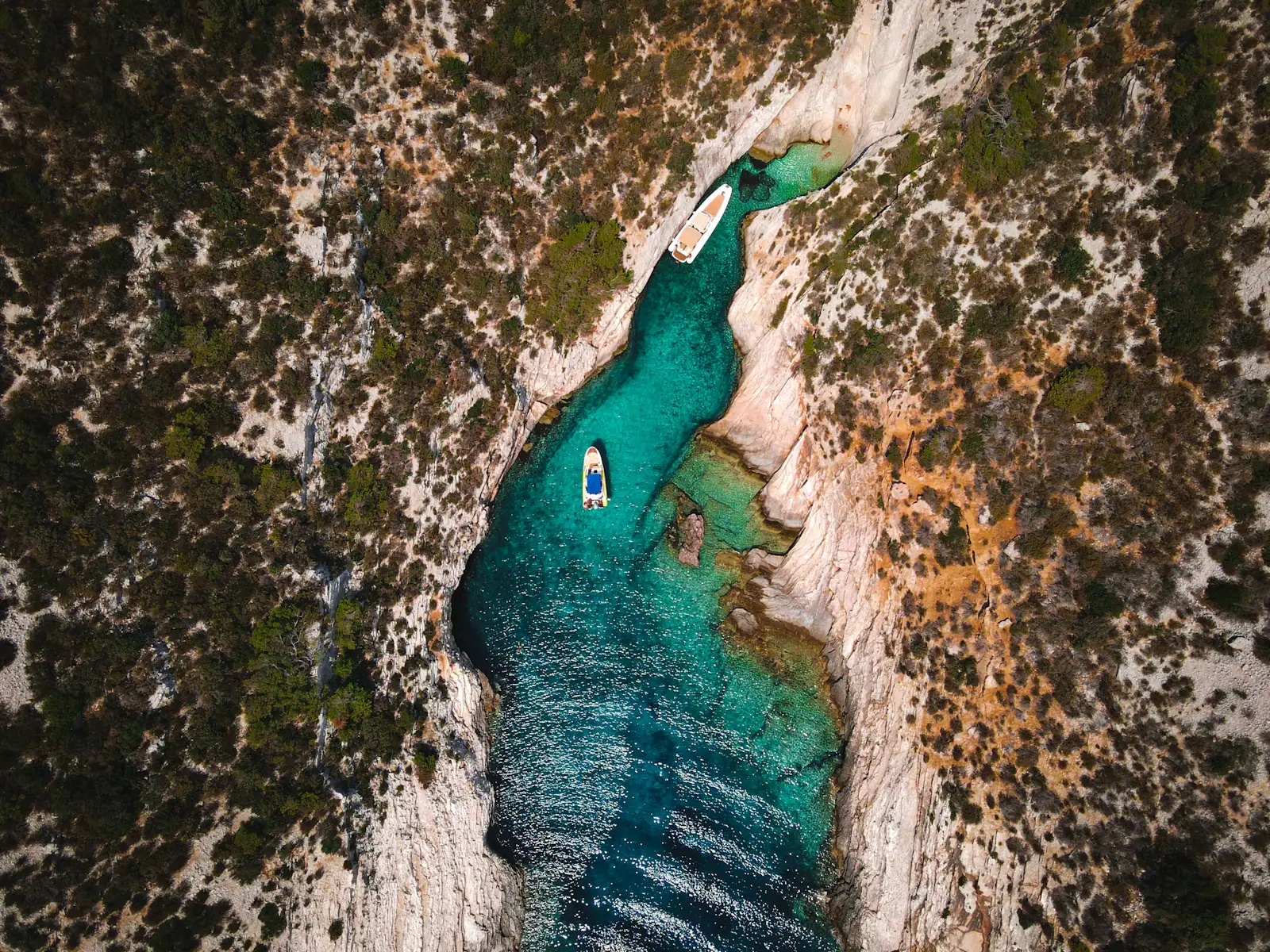 A small boat in a narrow turquoise channel between rocky islands on the Croatian Adriatic coast