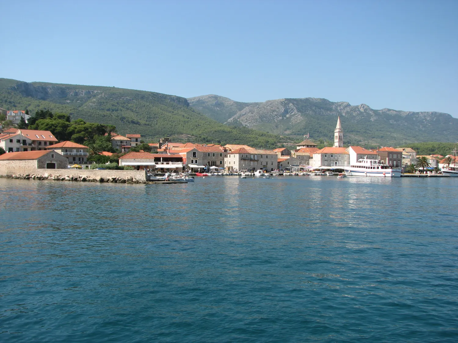 The harbour front of Jelsa on the north coast of Hvar seen from the sea, with wooded hills behind