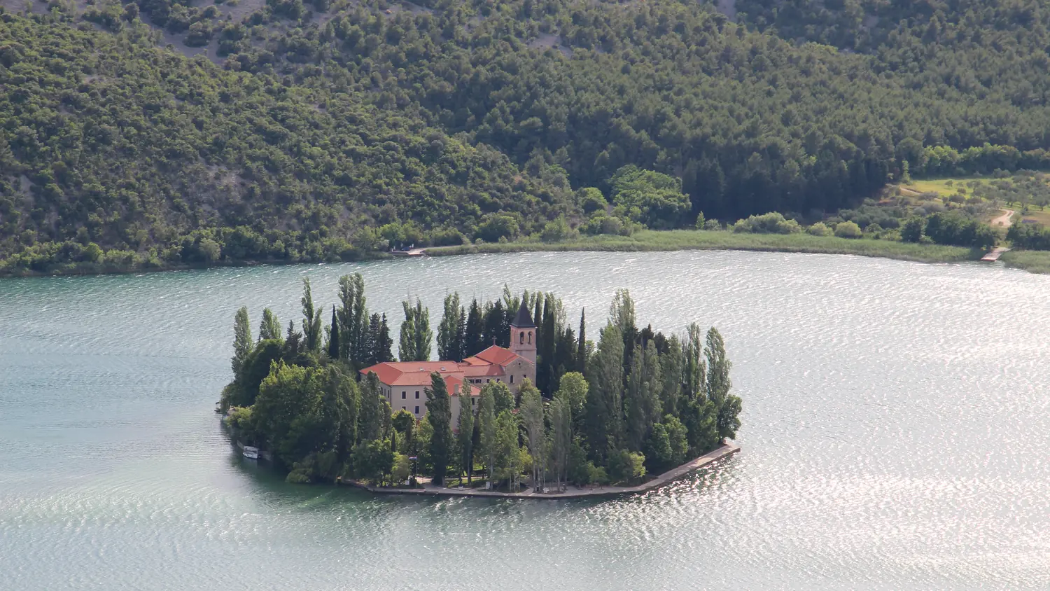 The island monastery of Visovac on the Krka river surrounded by green hills, Croatia