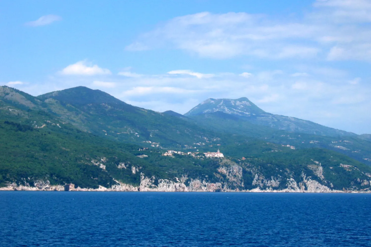 Steep green mountain slopes dropping straight into the deep blue Kvarner bay, Croatia