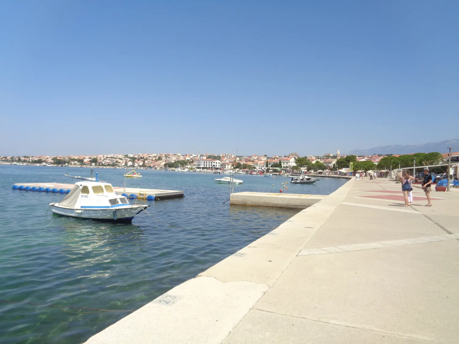 The seafront promenade of Novalja on the island of Pag with moored boats and the town behind, Croatia