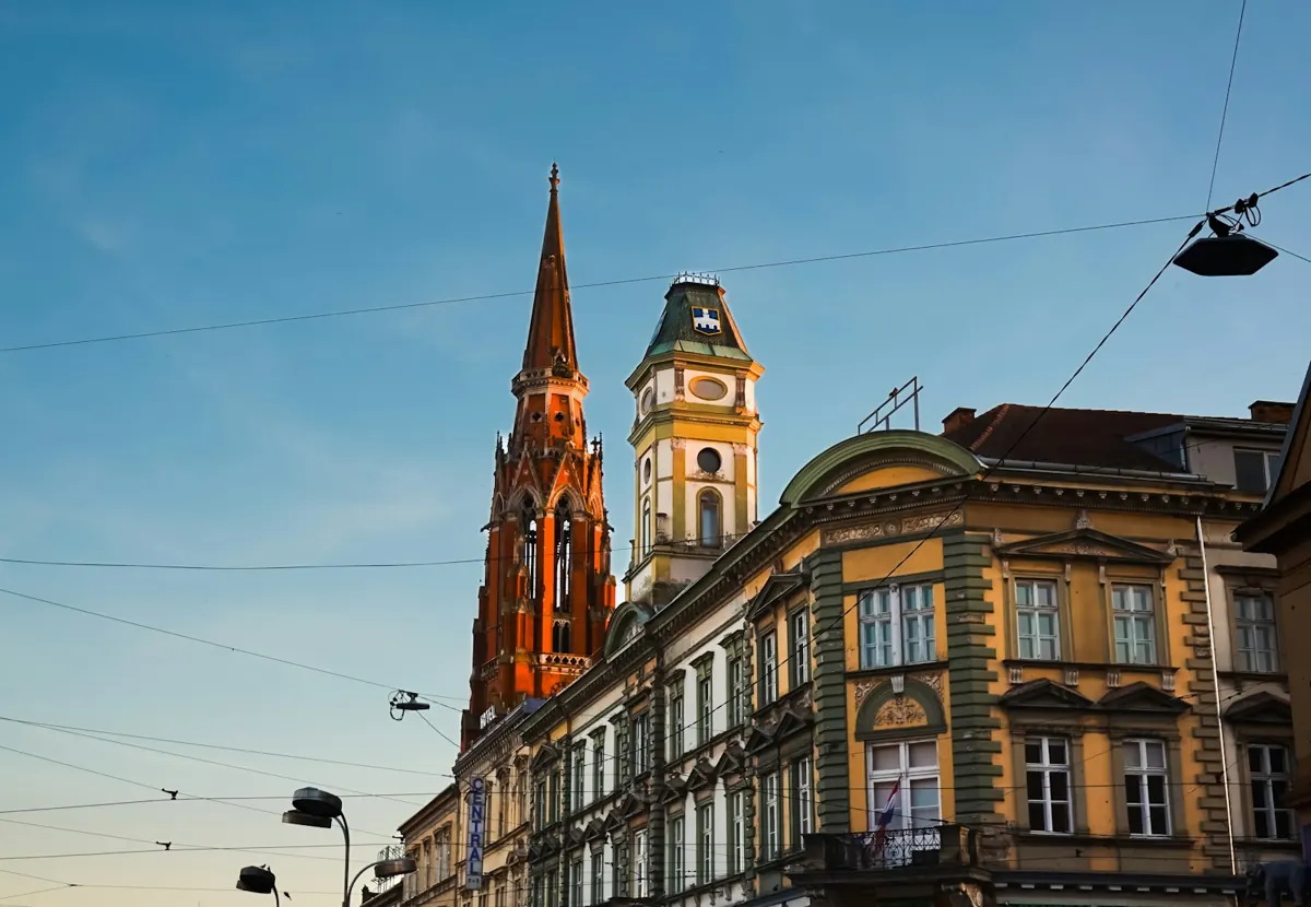 Street in central Osijek with the red brick cathedral tower rising above historic buildings
