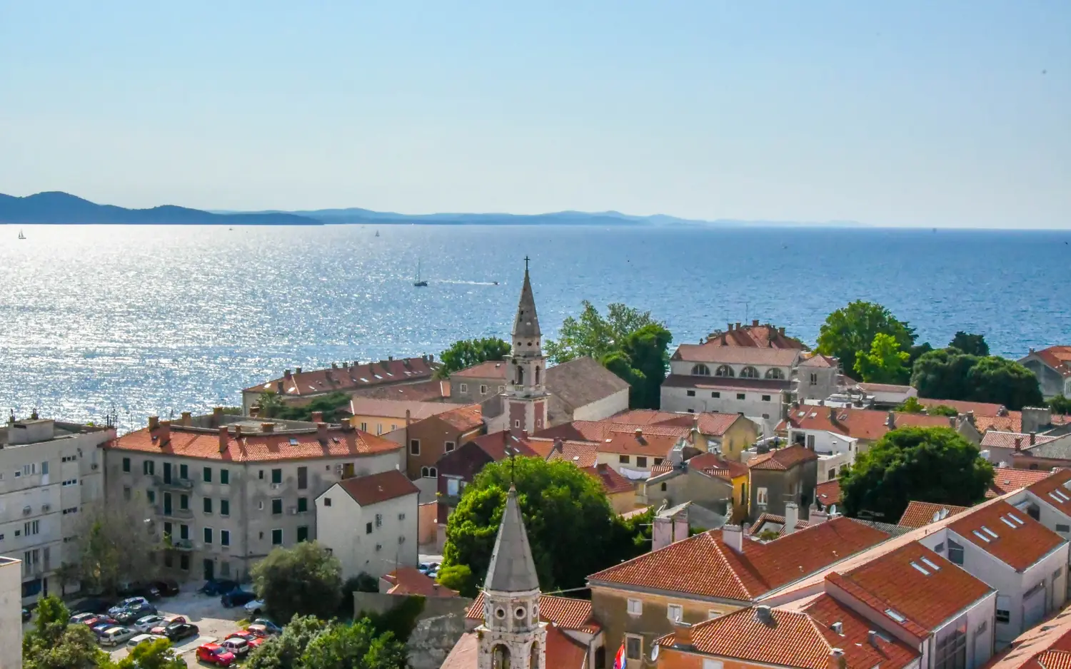 Red-tiled roofs and church towers of the old town of Zadar with the Adriatic and offshore islands behind, Croatia
